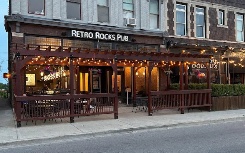 Front view of Retro Rocks Pub's exterior, showcasing its inviting outdoor seating area and warm lighting.